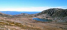 Vue d'un lac bleu et de collines herbacées et érodées