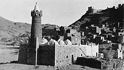 Partial view of Dhala in 1937, with the main mosque in the foreground. Atop the hill is the castle where the hereditary Amir of Dhala resided. Dhala, 65 miles or 105 kilometres north of Aden, lies 4,800 feet or 1,460 metres above sea level. It was then one of the states of the Aden Protectorate, strategically located near the border of the Protectorate and what was then the Imamate (Kingdom) of Yemen