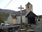 Une croix monumentale avec en arrière-plan, l'église Saint-Michel