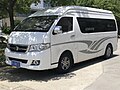 Camionette blanche au devant en pente avec longues fenêtres sur les côtés.