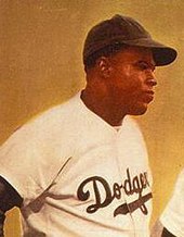 A black man in a baseball uniform, standing in front of a yellow screen and looking away from the camera, in a promotional poster for a film.