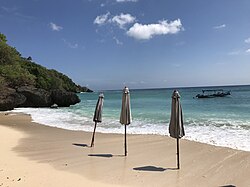 view of Padang Padang Beach with turquoise waters, golden sand, and beach umbrellas