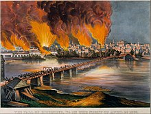 bridge in foreground going across river to city landscape that has flames reaching upwards
