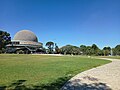 Foto del Planetario y el parque que se extiende por delante. Se ve un camino que une el edificio con el lugar de donde se tomó la imagen.