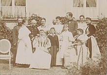 Group of men, women and two older children wearing 19th century formal wear.