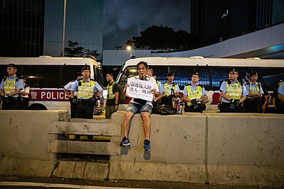 示威人士坐在路壆展示标语