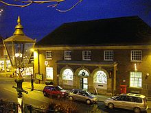 photo of the post office taken at evening time. A gas lantern stands in the foreground.