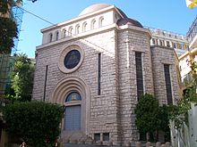 Image en couleur de la façade d'un édifice en pierre avec à son centre un portail surmonté d'une rosace