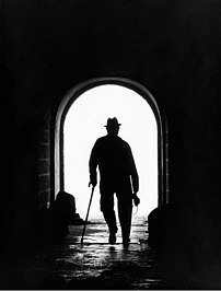 Silhouette en contre-jour d’un homme marchant avec une canne dans un tunnel, appareil photo en main. À Alcobaça, dans la baie de São Martinho do Porto (Portugal). (définition réelle 1 311 × 1 729)