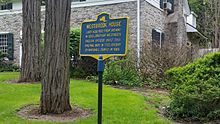 a picture of the rusted marker with the house in the background