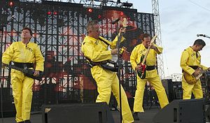 Devo onstage, wearing their trademark bright yellow radiation suits