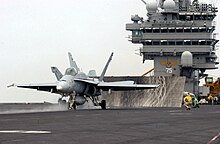 Chasseur F/A-18 sur le pont d'envol, prêt au catapultage.