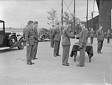 Divers officiers militaires au garde-à-vous. Un militaire se voit remettre une médaille par un autre.