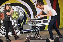 Male and female electronic duo performing together.