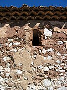 Vista del exterior de la ermita de San Pedro en El Cuervo (Teruel), con detalle de la mampostería del muro meridional, ventanuco y alero.