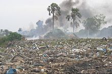 A dumpsite with smoke coming from it.