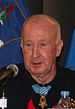 Older bald man wearing black shirt with medal around neck