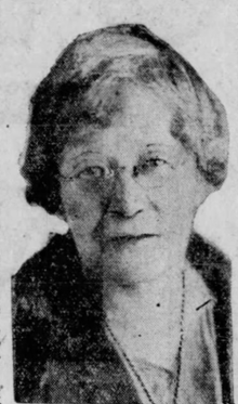 Photo of an elderly woman with short hair and eye glasses.