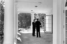 The Kennedys are pictured conferring outside the White House on a covered porch on October 3