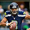 Headshot of Russell Wilson in uniform and helmet running with the football