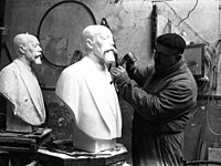 Photo en noir et blanc d'un homme taillant un buste blanc