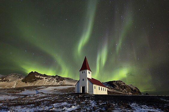 „The aurora or northern lights shot with a Canon camera over the church at Vik in Iceland on a clear night.“ von AstroAnthony, CC BY-SA 4.0