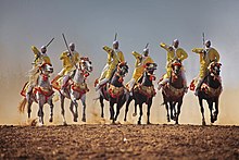 Groupe de cavaliers hommes en ligne et au galop.