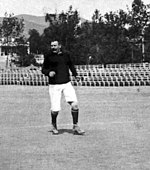 B&W photo of middleaged man standing on a pitch with a football
