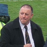 Photo of a man in a black coat and black tie