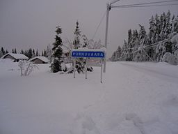 Vägen in till Purnuvaara med ortsskylten. Fotot tagit i västlig riktning, december 2015.