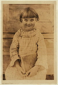 Photo d'enfant souriante, assise, de face