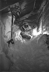 A man crawls through a passageway filled with snow