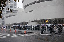 Photographie prise de la rue montrant un file d'attente de visiteurs devant le musée.