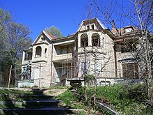 Photographie en couleur d'une grande villa située dans un environnement boisé.