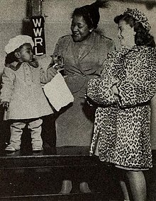 A photograph of a woman standing between two children dressed in fur coats.