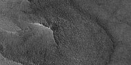 In a close-up of the east (right) side of the previous image, polygons on a lobe at the crater's margin are thought to indicate ice lies under the protective top.