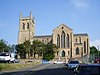 A large stone church from the south with a large transept and a west tower