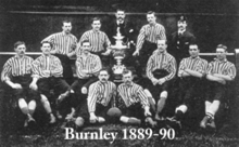 A black and white image of a football team with a trophy in the middle