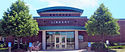 A single-story brick library with a tall front entrance on a clear summer day, pictured 2013