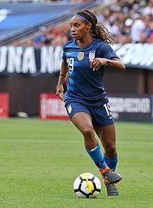 Crystal Dunn running with a soccer ball at her feet.