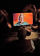 Jim Stokes watching a video of himself in the Dakota Family Theater.