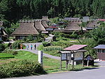 Wooden houses with thatched roofs in a mountain setting.