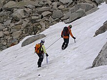 Deux alpinistes encordés progressant sur une pente de neige, corde tendue