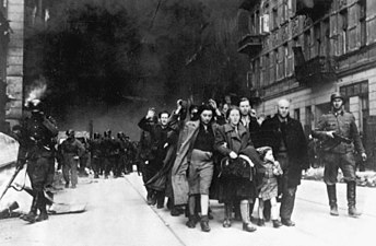 IPN copy #7 Forcibly pulled out of bunkers Captured Jews are led by Waffen SS soldiers to Umschlagplatz. In the back Nowolipie 62 & 63. See file page for possible identity of depicted people. The SS man at right has the "Totenkopf" Insignia on his collar.