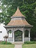 A wooden gazebo with a pointed roof