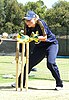 A young woman in sports gear and gloves catching a cricket ball