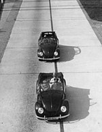 Black and white image of two black small convertibles driving on the Reichsautobahn
