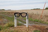 A sculpture consisting of two white posts holding a black spectacles frame in Buddy Holly's characteristic style