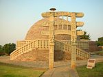 A heavily decorated gate in front of a stupa.