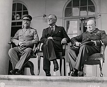 Three men, Stalin, Roosevelt and Churchill, sitting together elbow to elbow